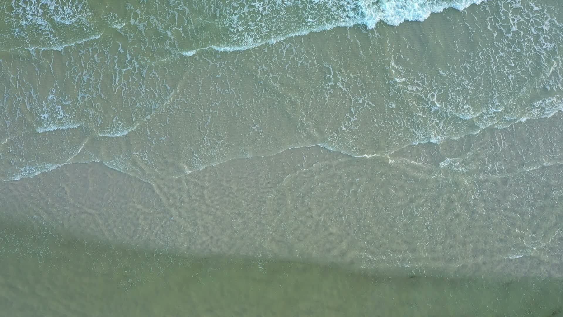 Aerial of a quiet, empty white-sand beach and clear Gulf water