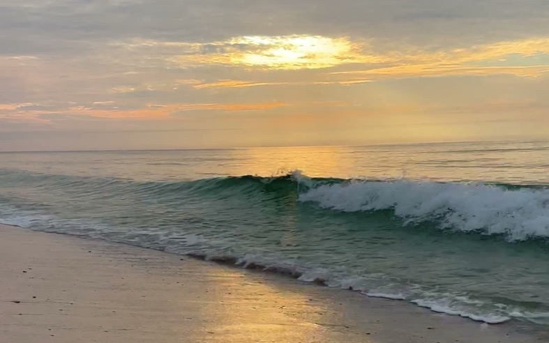 A golden winter sunset over a breaking wave on the Gulf in Gulf Shores, Alabama
